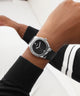 Close-up of a wrist wearing a black watch with a white background