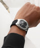 Close-up of a wrist wearing a black watch with a white background