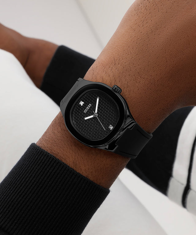 Black GUESS Mens BLACK Analog Watch on a person's wrist with a blurred background