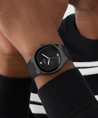 Black GUESS Mens BLACK Analog Watch on a person's wrist with a blurred background