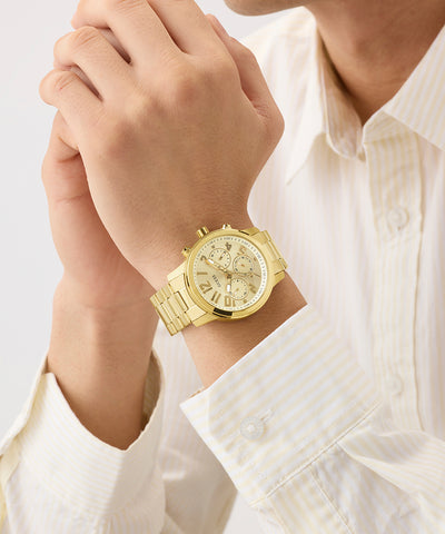GUESS Mens Gold Tone Analog Watch on a person's wrist with a light background