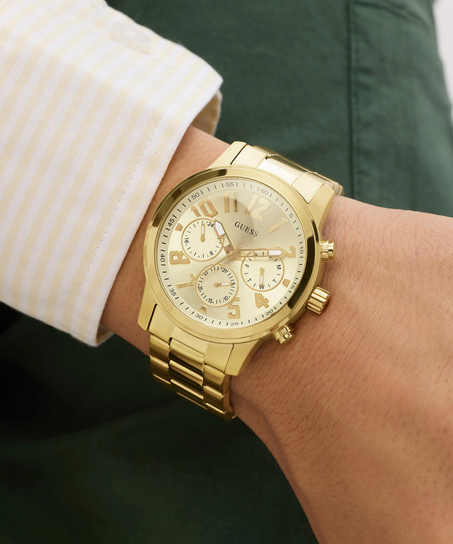 GUESS Mens Gold Tone Analog Watch on a person's wrist with a blurred background