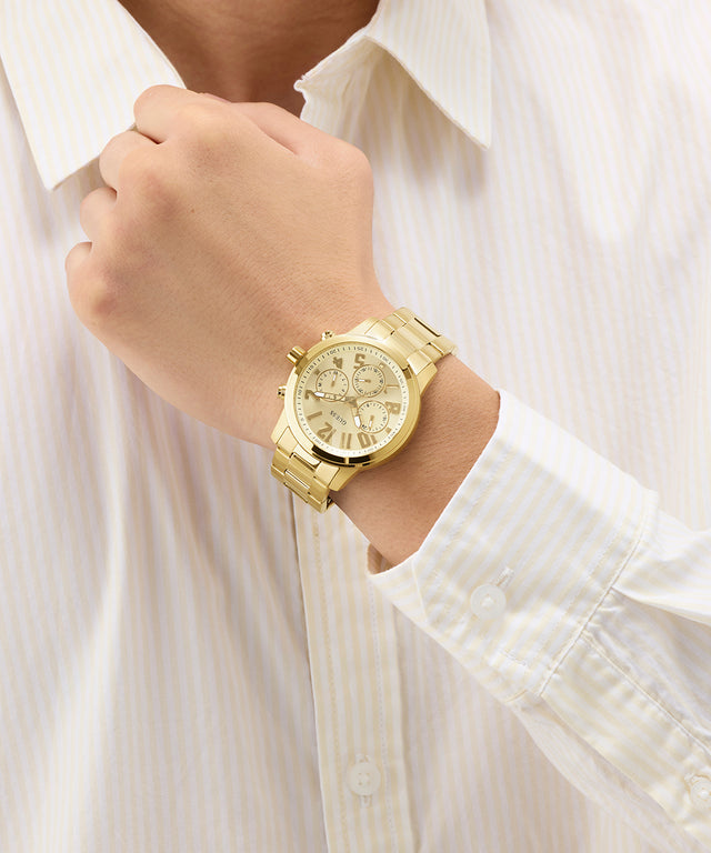 GUESS Mens Gold Tone Analog Watch on a person's wrist with a white shirt background