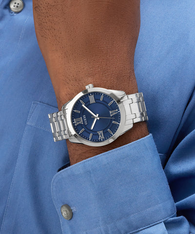 GUESS Mens SILVER TONE Analog Watch with blue dial on a wrist, wearing a blue shirt.