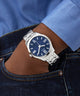 GUESS Mens SILVER TONE Analog Watch with a blue face on a wrist, wearing a blue shirt and jeans.