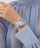 Silver GUESS Ladies Silver Tone Multi-function Watch on a wrist with a light blue dress