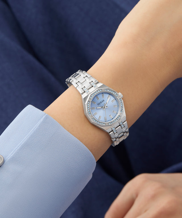 Silver GUESS Ladies Silver Tone Analog Watch on a wrist with a blue background