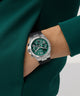 Green GUESS Mens Equity Black Silver Tone Analog Watch on a person's wrist with a green sweater