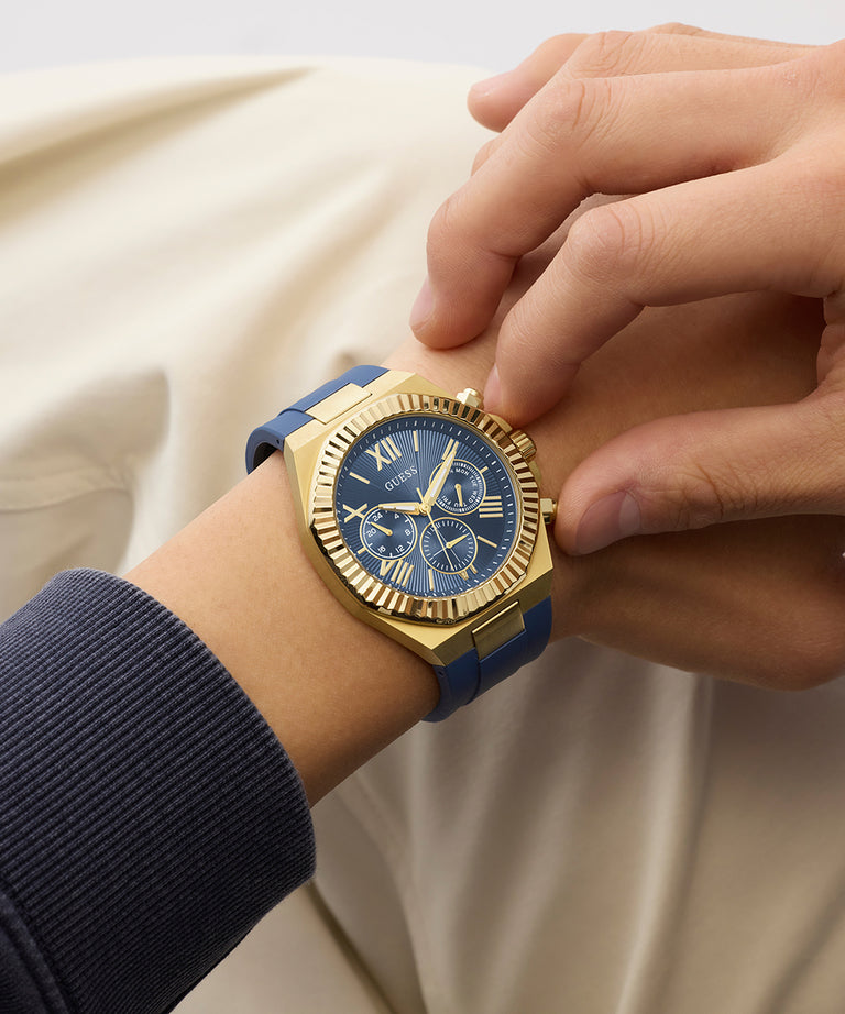 Gold and blue GUESS Mens Equity Blue Gold Tone Analog Watch on a wrist with a neutral background