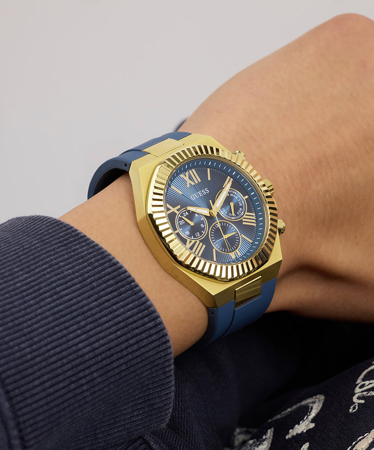 Gold and blue GUESS Mens Equity Blue Gold Tone Analog Watch on a wrist with a gray background