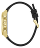 A close-up side view of a watch with a gold-tone case and three chronograph buttons, paired with a black silicone strap and gold buckle, shown on a plain white background.