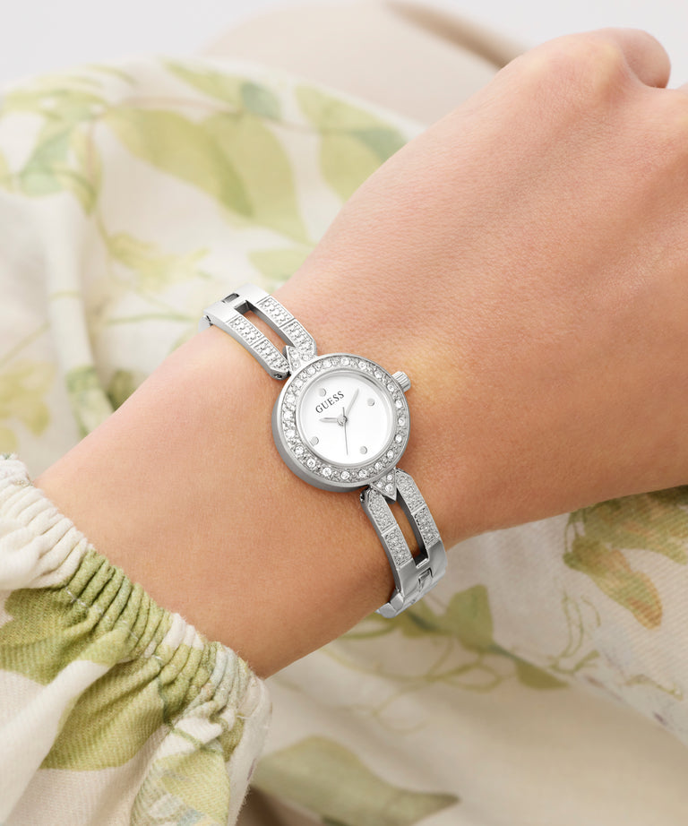 Silver Guess watch on a wrist with a floral background