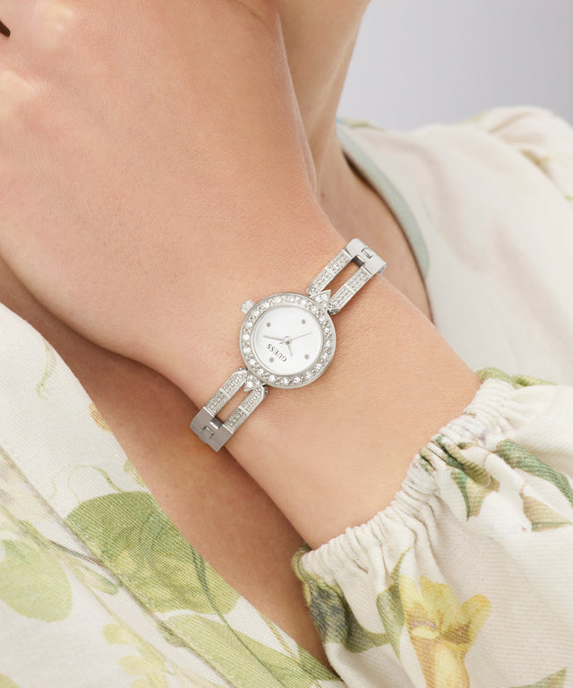 Silver GUESS Ladies Silver Tone Analog Watch with a floral-patterned dress on a neutral background