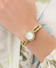 GUESS Ladies Gold Tone Analog Watch on a wrist with a floral-patterned garment