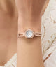 Rose gold GUESS Ladies Rose Gold Tone Analog Watch on a wrist with a blurred background