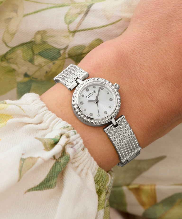 Silver Guess watch on a wrist with a floral background