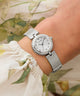Silver Guess watch on a wrist with a floral background