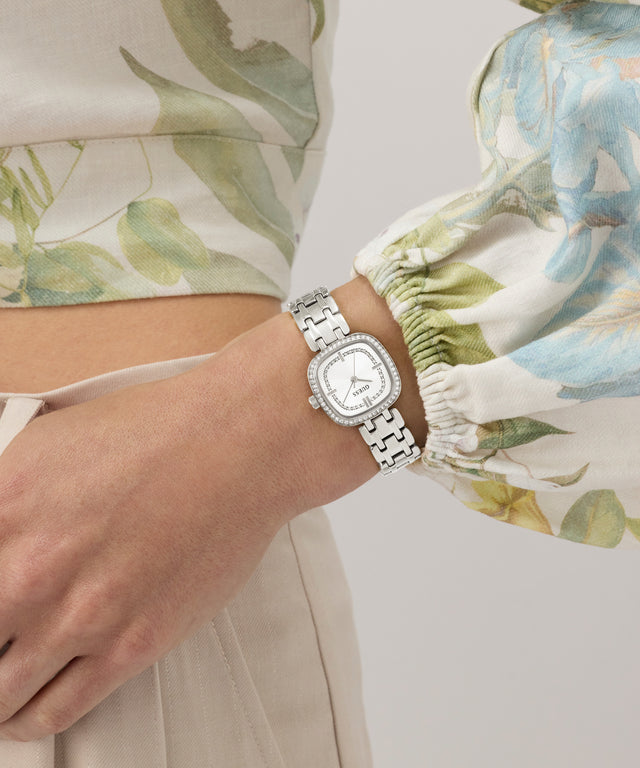 GUESS Ladies Hazel Silver Tone Analog Watch on a wrist with a floral-patterned shirt