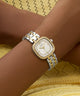 GUESS Ladies Hazel 2-Tone Analog Watch on a wrist with a yellow textured background