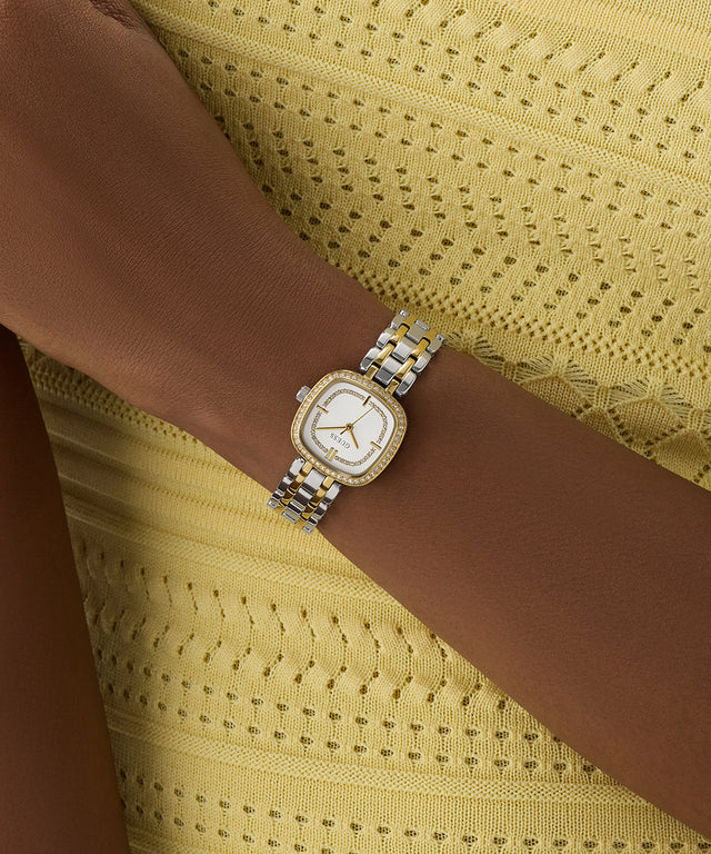 GUESS Ladies Hazel 2-Tone Analog Watch on a wrist with a yellow textured background