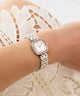 GUESS Ladies Hazel 2-Tone Analog Watch on a wrist with a white lace background