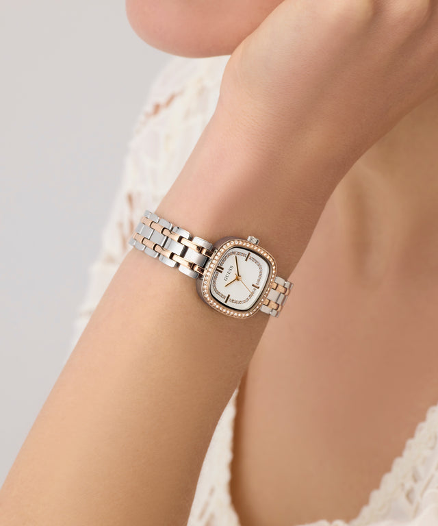 Rose gold and silver GUESS Ladies Hazel 2-Tone Analog Watch on a wrist with a blurred background