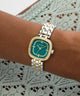 GUESS Ladies Hazel 2-Tone Analog Watch with green face on a wrist against a lace background