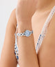 Silver GUESS Ladies Siren Silver Tone Analog Watch on a person wearing a patterned bikini against a light background