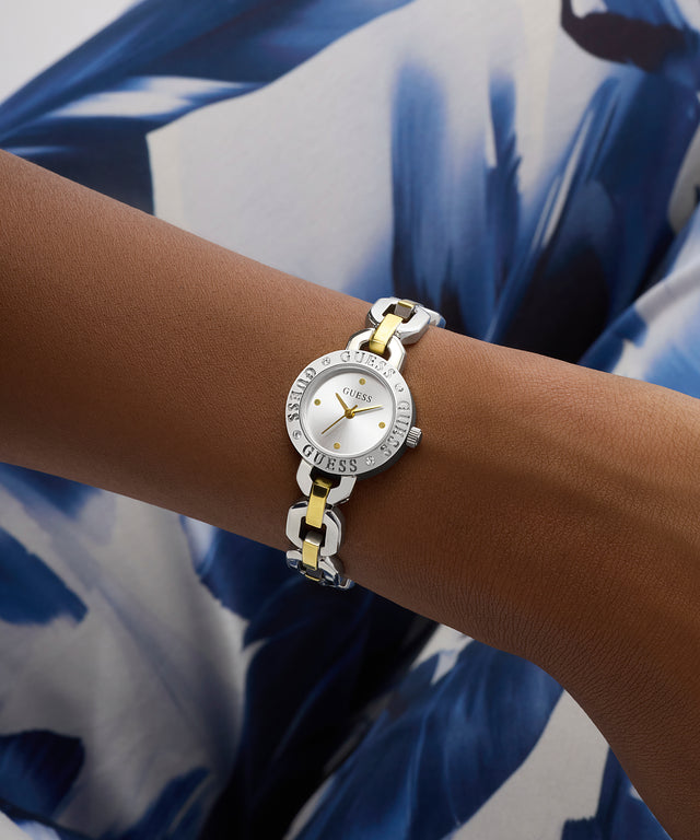 Gold and silver watch on a wrist with a blue and white patterned fabric background GW1019L3