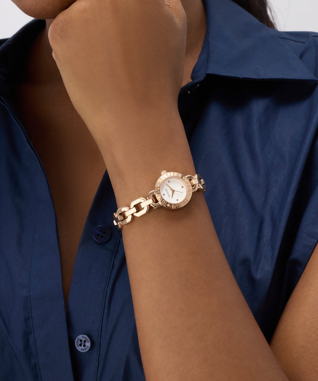 Gold bracelet GUESS Ladies Siren Rose Gold Tone Analog Watch on a wrist with a blue shirt background