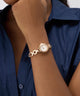 Gold bracelet GUESS Ladies Siren Rose Gold Tone Analog Watch on a wrist with a blue shirt background