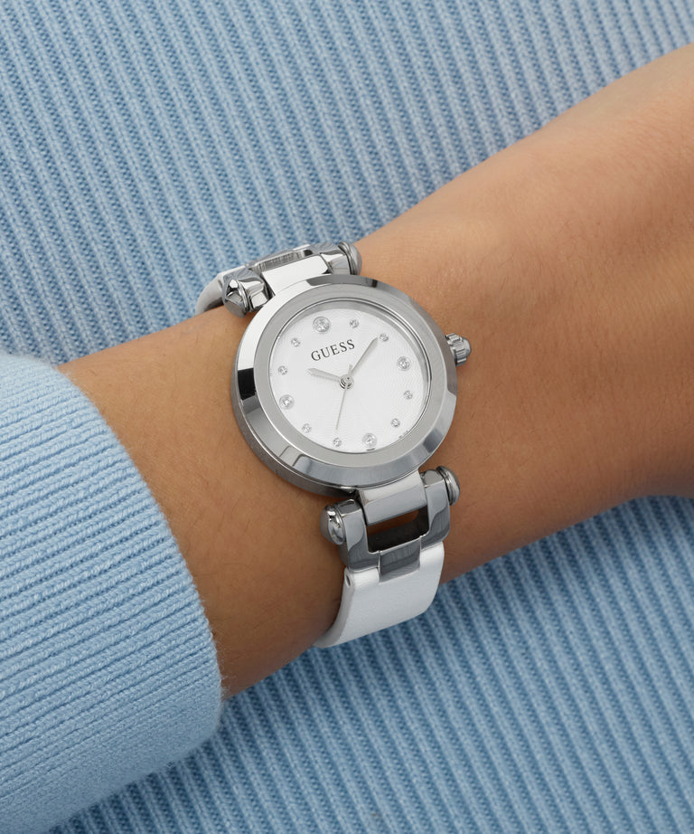 Silver Guess watch on a wrist with a blue background
