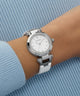 Silver Guess watch on a wrist with a blue background