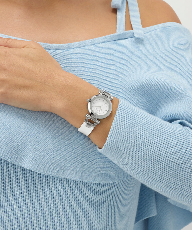 Person wearing a silver watch with a white strap on a light blue sweater.