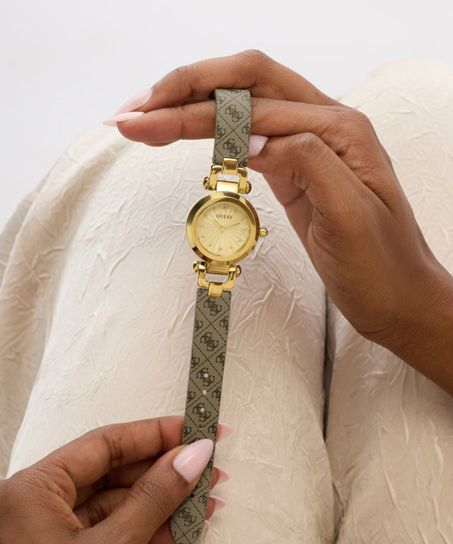 Gold watch with a patterned strap held by hands against a white background