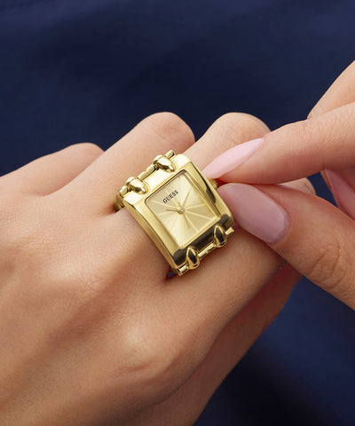 GUESS Ladies Mod Heavy Metal Gold Tone Analog Watch Ring with a square watch face on a hand against a dark background