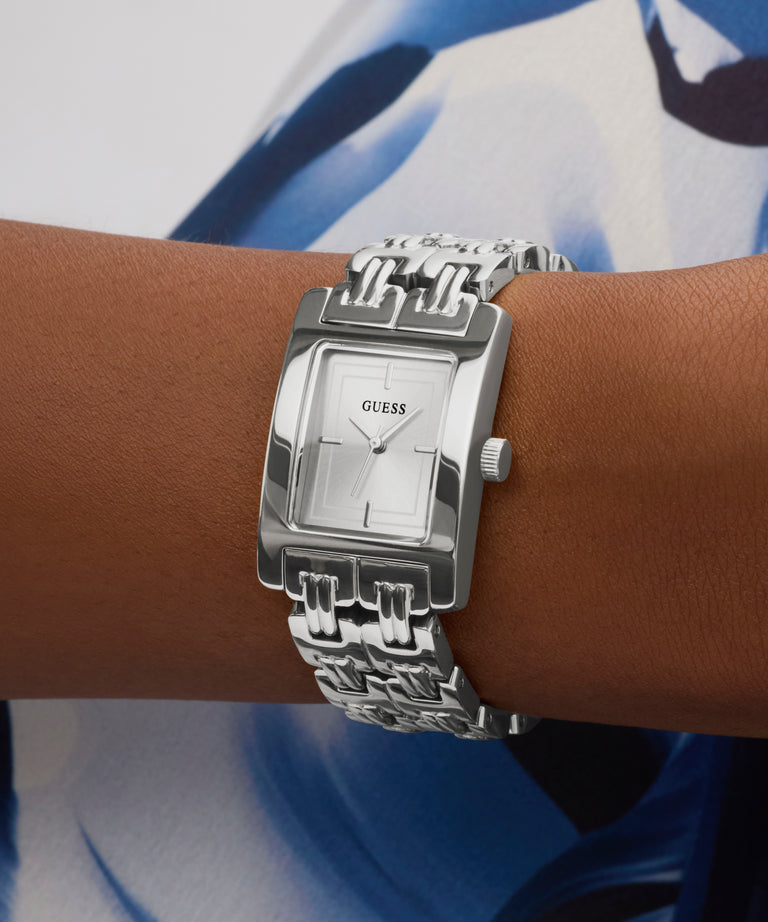 Silver Guess watch on a wrist with a blue and white background