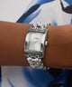 Silver Guess watch on a wrist with a blue and white background