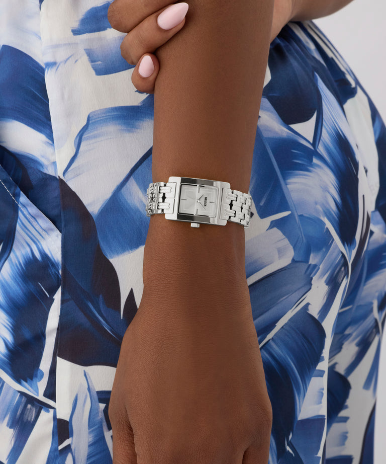 Silver GUESS Ladies Silver Tone Analog Watch on a wrist with a blue and white patterned fabric background