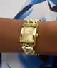 Gold GUESS Ladies Gold Tone Analog Watch on a wrist with a blue and white patterned background