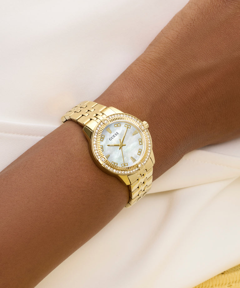 Gold watch with a white face on a wrist against a light background