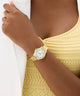 Gold watch on a wrist with a yellow top against a white background