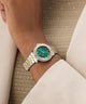 Close-up of a wrist wearing a silver and gold GUESS Ladies Colette 2-Tone Analog Watch with a green face.