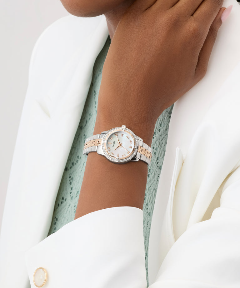 Close-up of a person wearing a silver and rose gold watch on a plain background