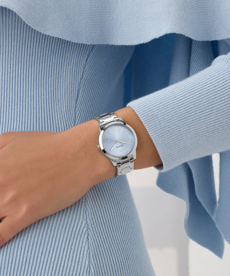 Silver watch on a wrist with a light blue sweater