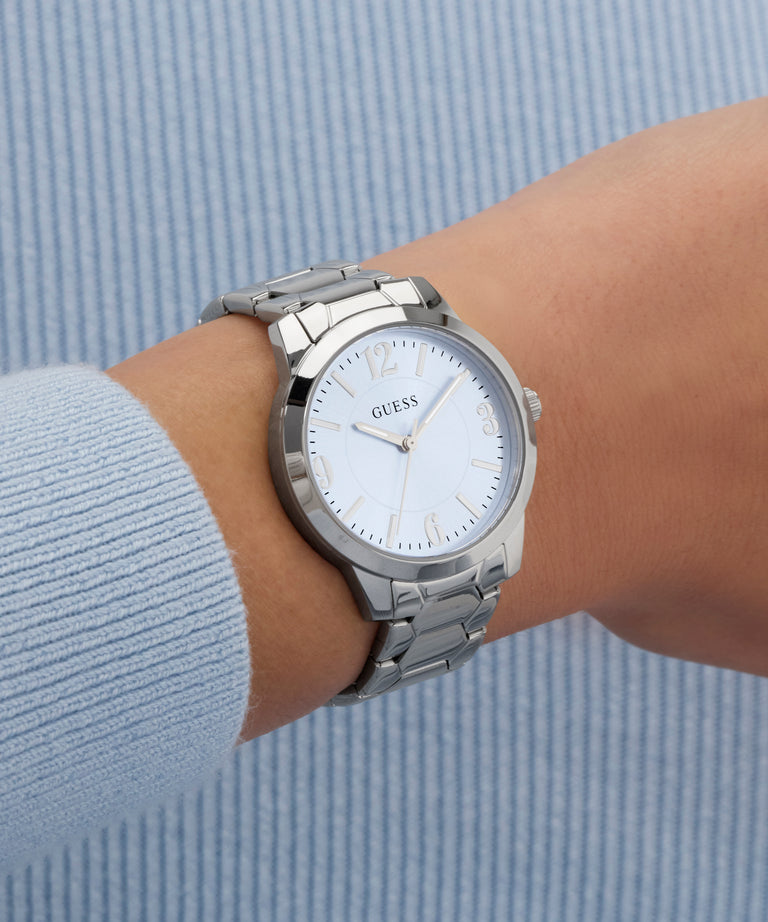 Silver watch on a wrist with a light blue background
