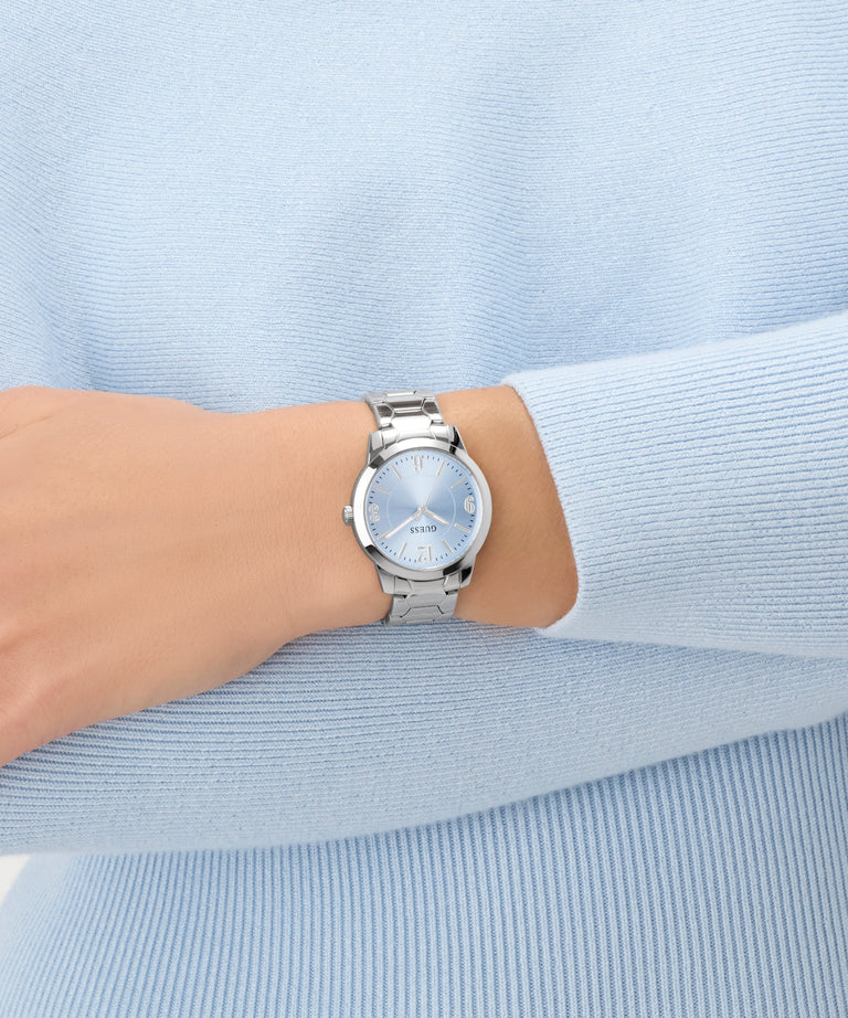 Silver watch on a wrist with a light blue background