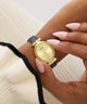 Gold watch on a wrist with a neutral background