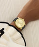 Gold watch on a wrist with a neutral background