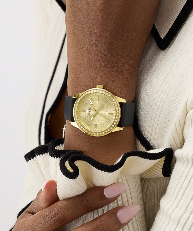 Gold watch with black strap worn on wrist against a neutral background